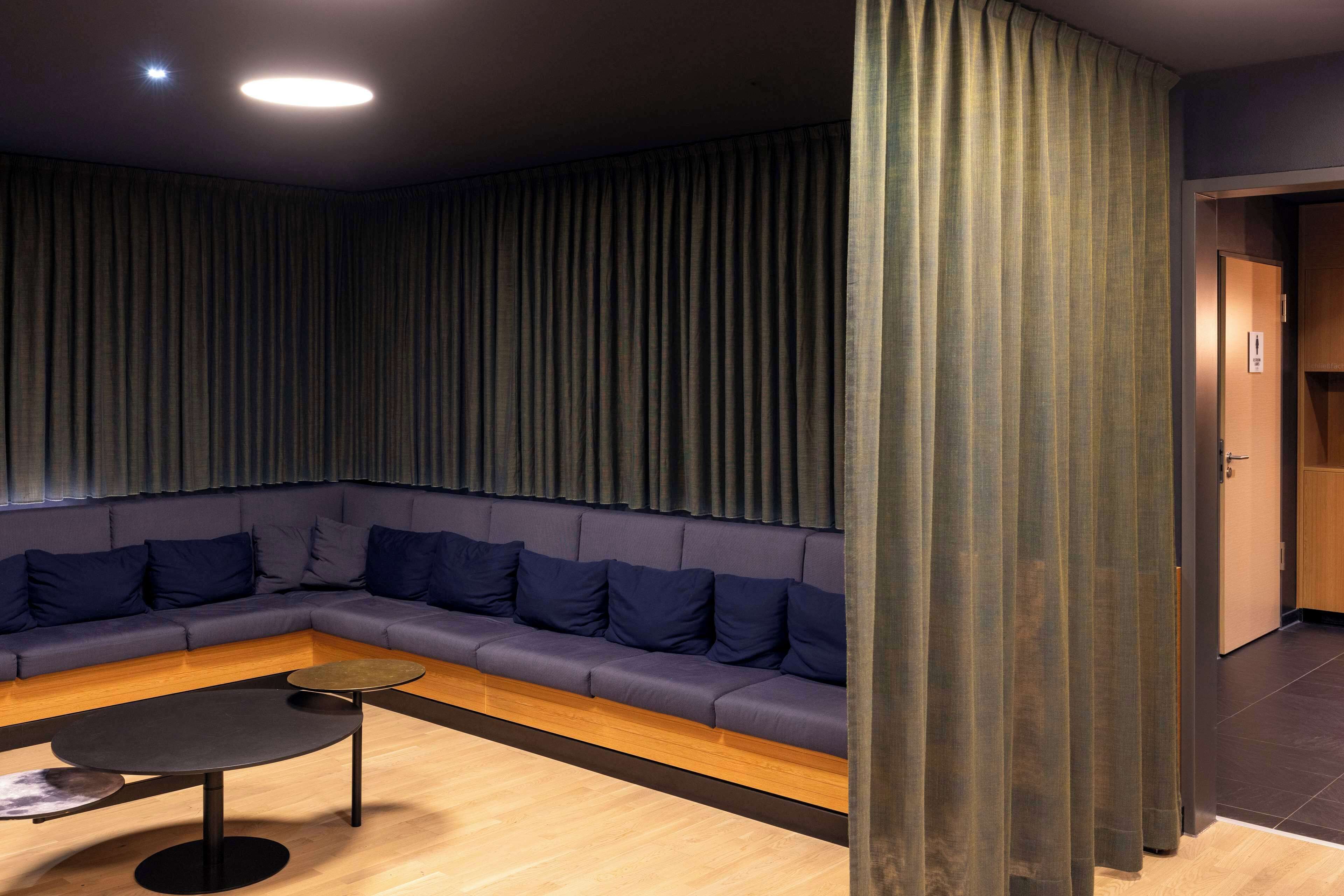 Un espace de détente moderne avec un canapé bleu foncé, une table ronde noire et un plancher en bois.
