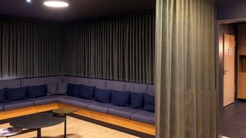 Un espace de détente moderne avec un canapé bleu foncé, une table ronde noire et un plancher en bois.