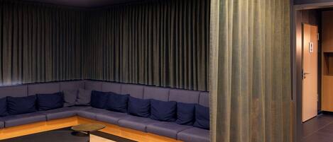 Ein moderner Lounge-Bereich mit einem dunkelblauen Sofa, einem runden schwarzen Tisch und Holzboden.