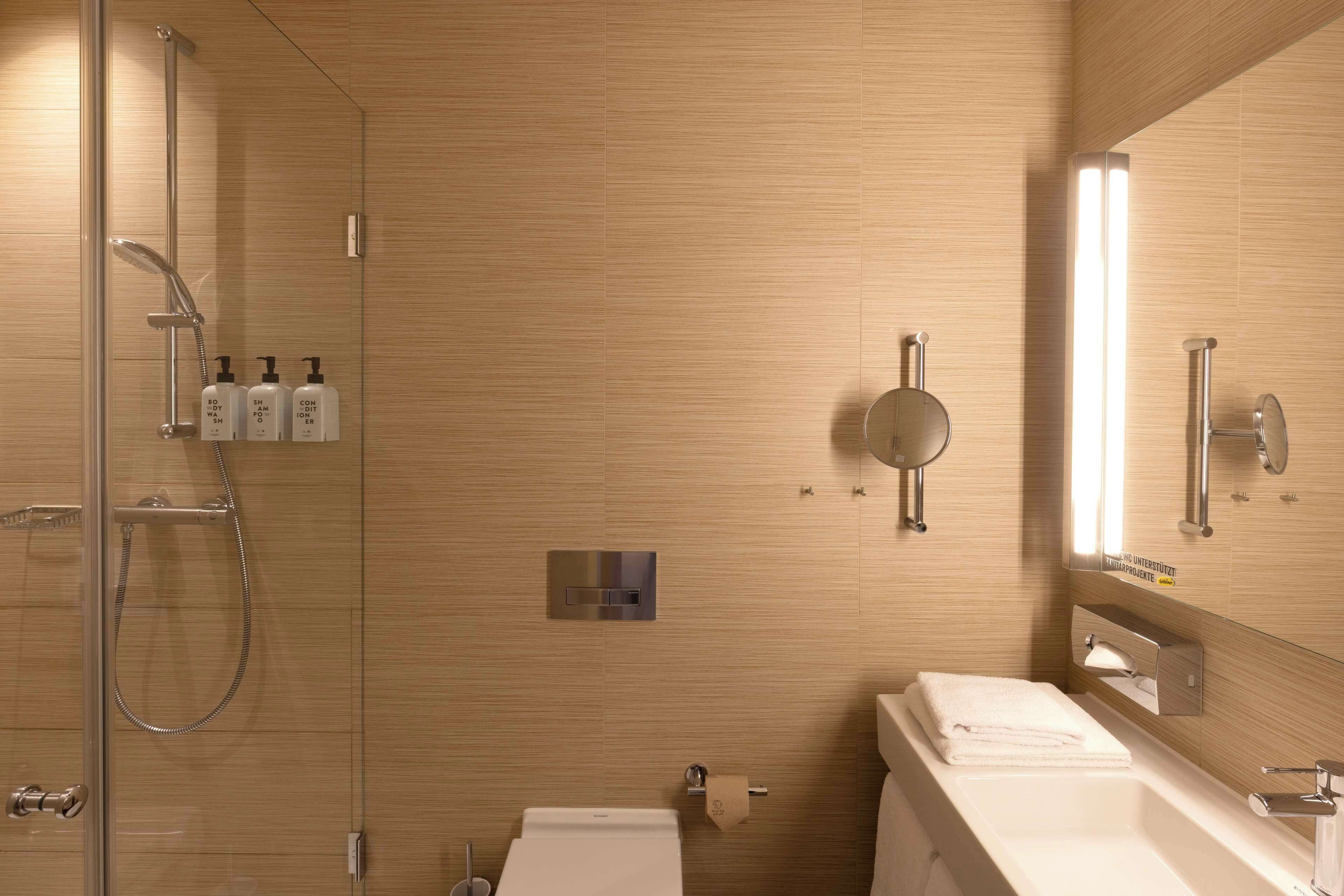 A modern bathroom with a glass-enclosed shower, a white sink, and a large mirror.