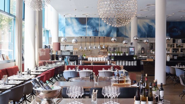 Un restaurante con mesas altas, sillas y una zona de bar.
