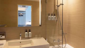 Un baño moderno con un lavabo grande, un espejo y una zona de ducha con mampara de vidrio.