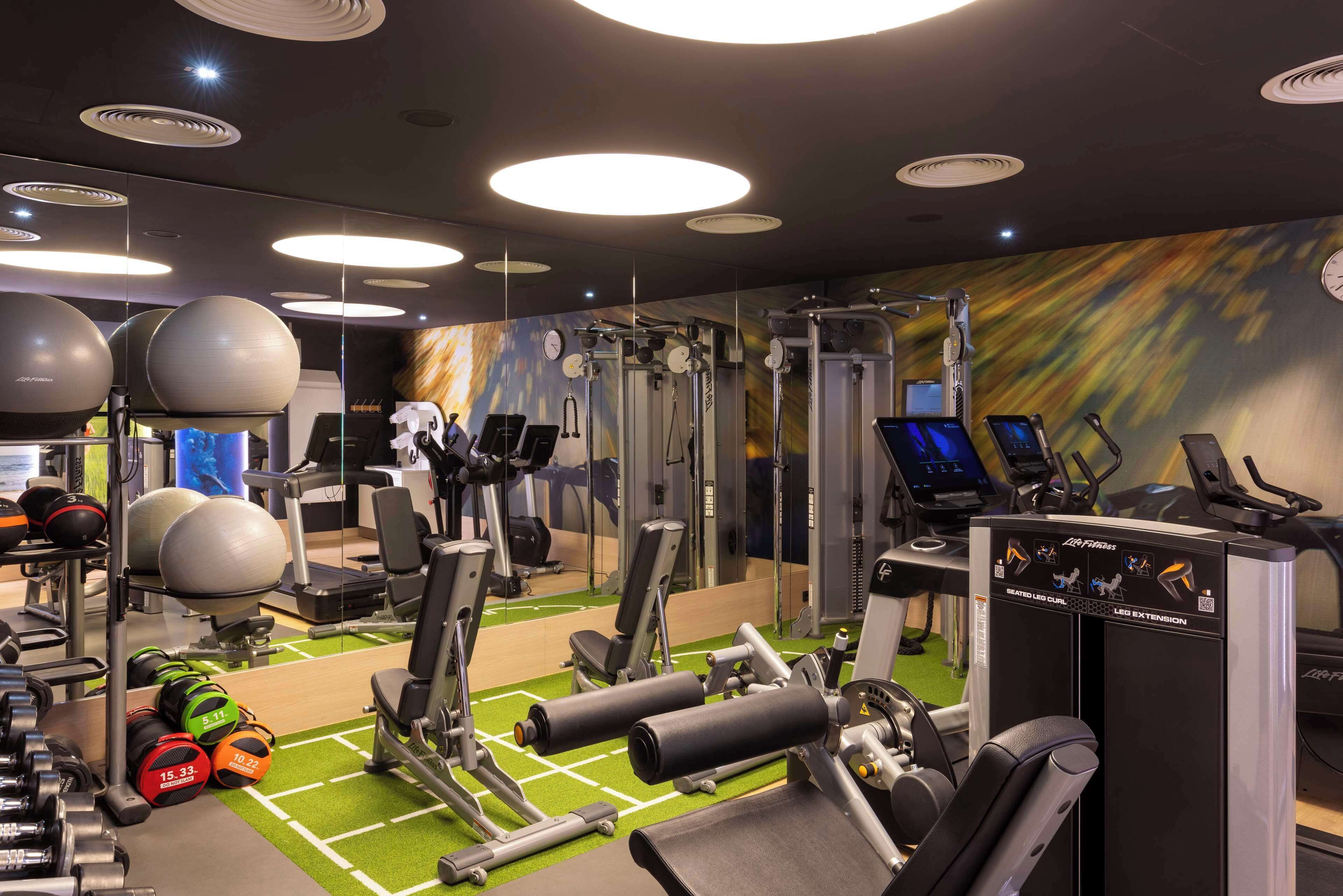A gym with exercise equipment, treadmills, and weights.