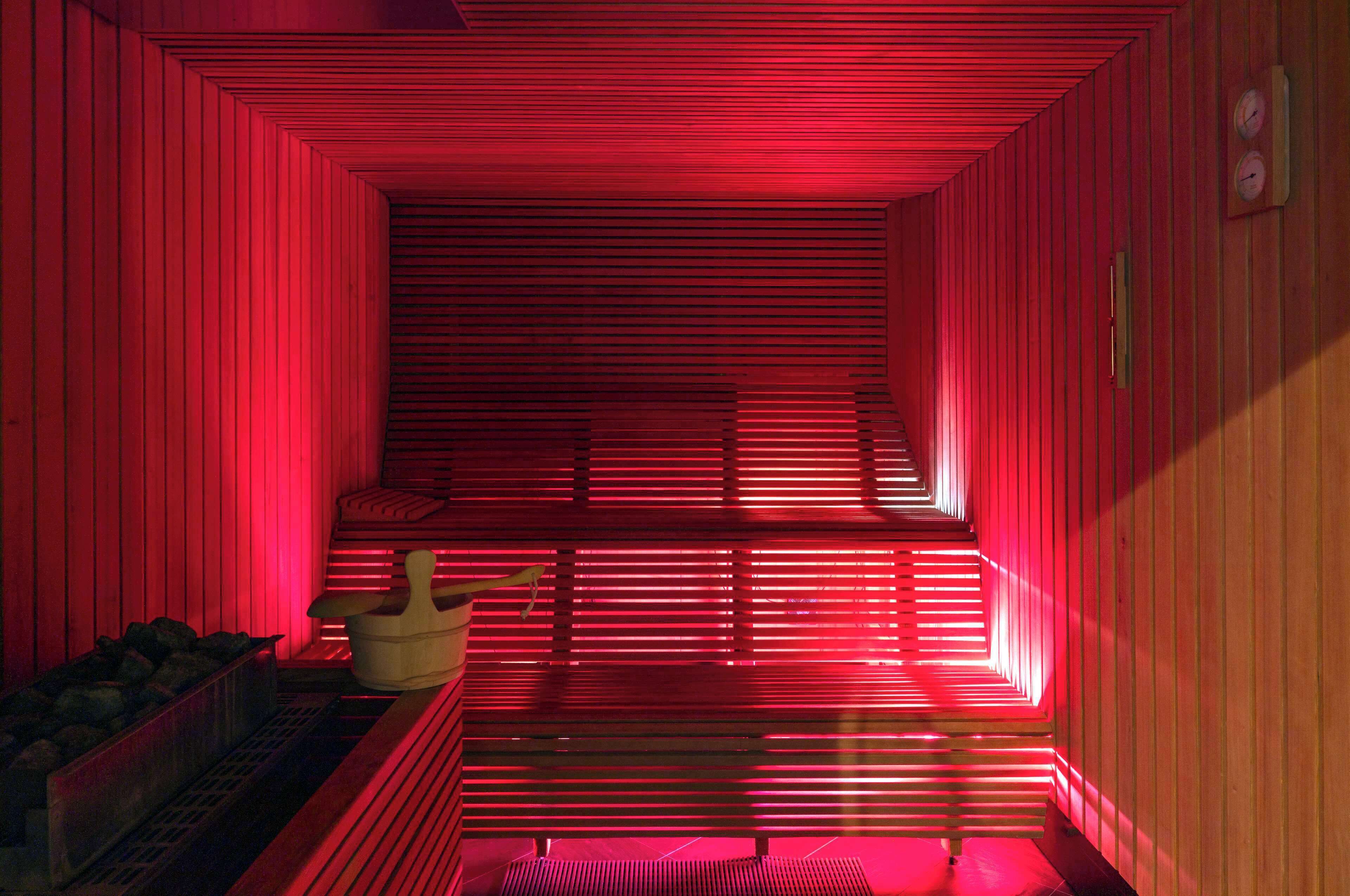 Een sauna met rode verlichting en houten wanden.
