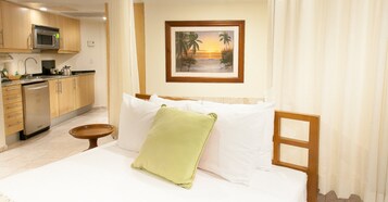 Una habitación de hotel con cama, una mesita, microondas y zona de cocina.