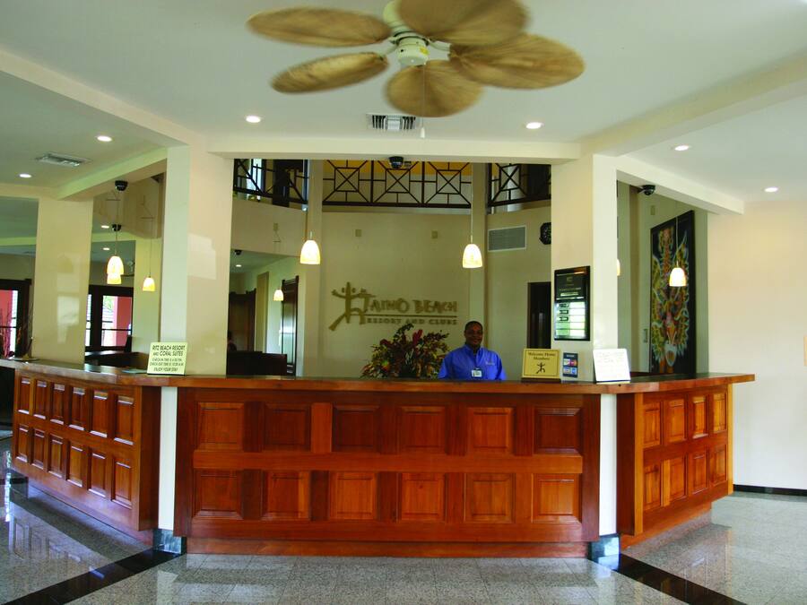 Un mostrador de recepción con un cartel que indica 'Ritchey Beach Resort and Club' y un cartel que dice 'Sala de Equipaje'.