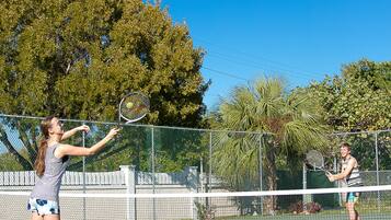 A tennis court with a net in the middle, surrounded by a chain-link fence.