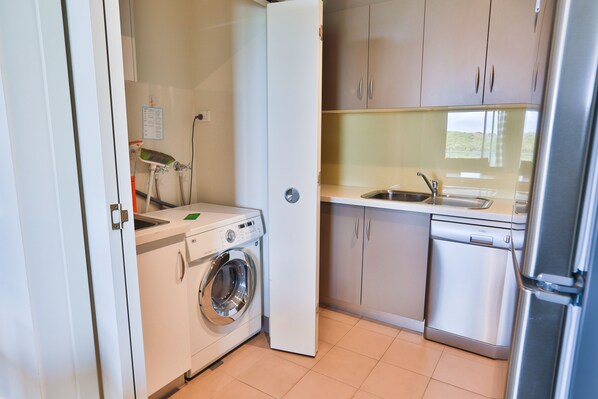 A compact kitchen with a washing machine, dishwasher, and a refrigerator.