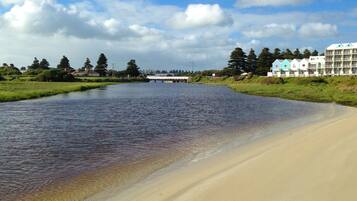 Overlooking a serene river, this hotel offers a tranquil beachside setting with lush greenery and a picturesque bridge.