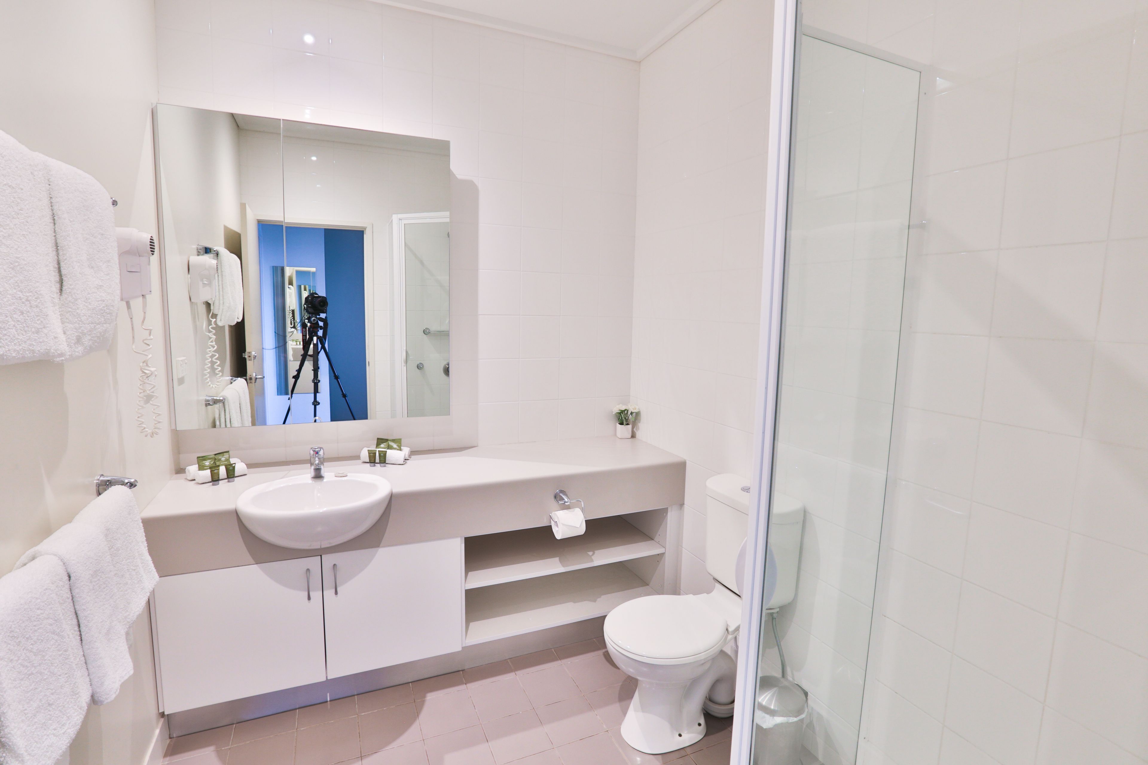 A modern bathroom with a white sink, mirror, and toilet.
