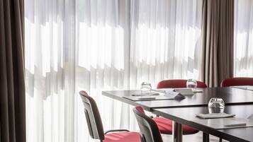 A conference room with a table, chairs, and a large window with sheer curtains.