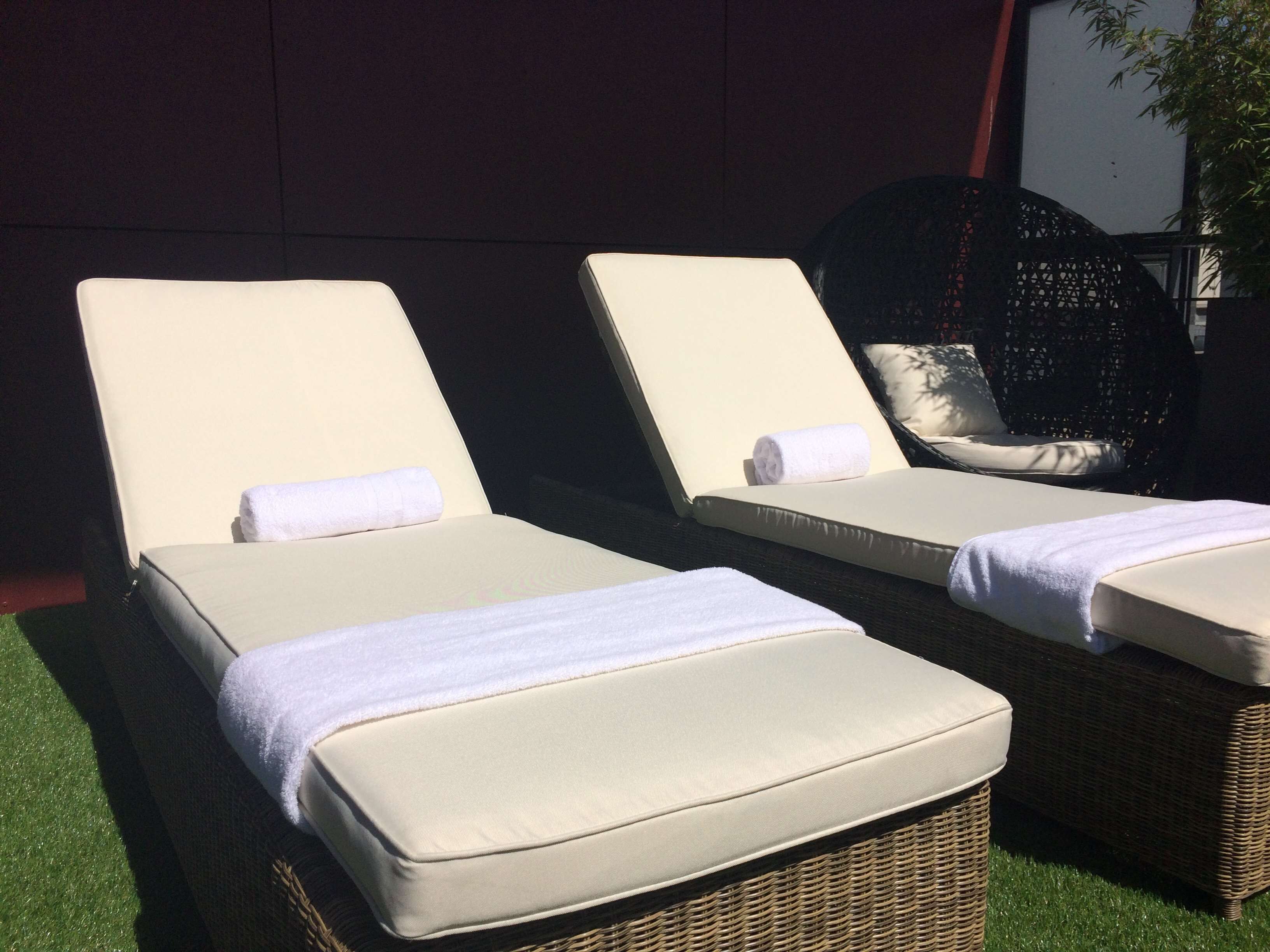 Two lounge chairs with white cushions and a wicker base, positioned on artificial grass.