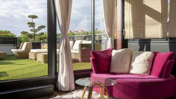 Una sala de estar moderna con un sofá rosa, una mesa de centro de vidrio y muebles de mimbre.