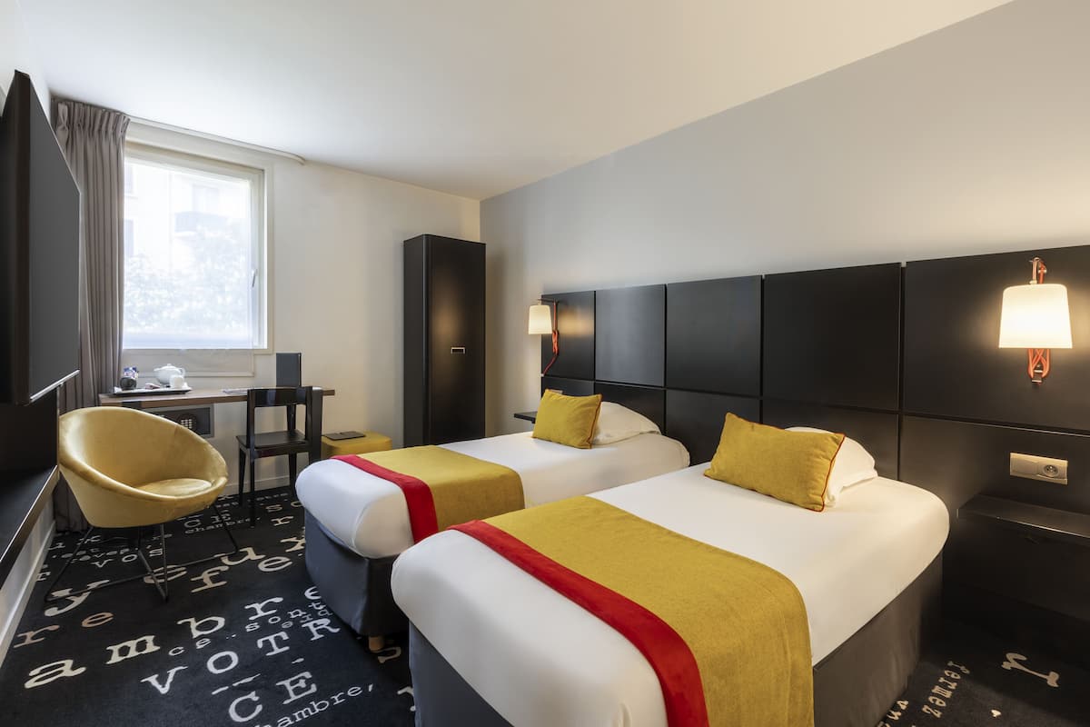 Una habitación de hotel con dos camas, un escritorio, una silla y un televisor.