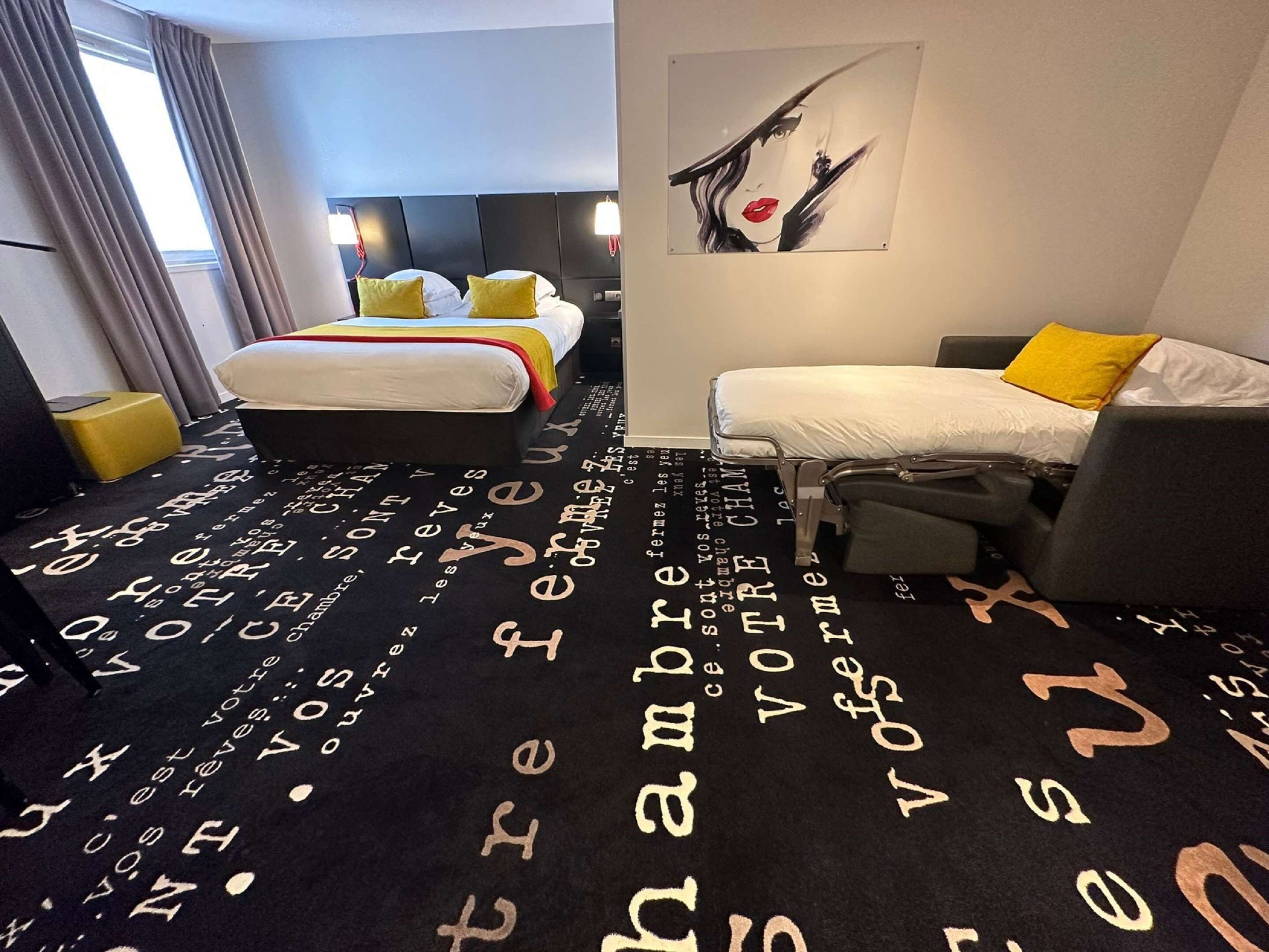 Ein Hotelzimmer mit Bett, einer Couch und einem Kunstwerk an der Wand.
