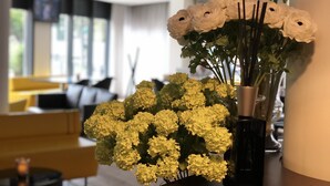 A reception area with a vase of white flowers and yellow hydrangeas on a wooden table. - Best Western Plus Thionville Centre (Thionville)