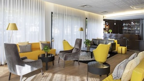 A modern living room with a yellow sofa, grey armchairs, and a black coffee table. There is a bar area with a wine rack and a plant. - Best Western Plus Thionville Centre (Thionville)