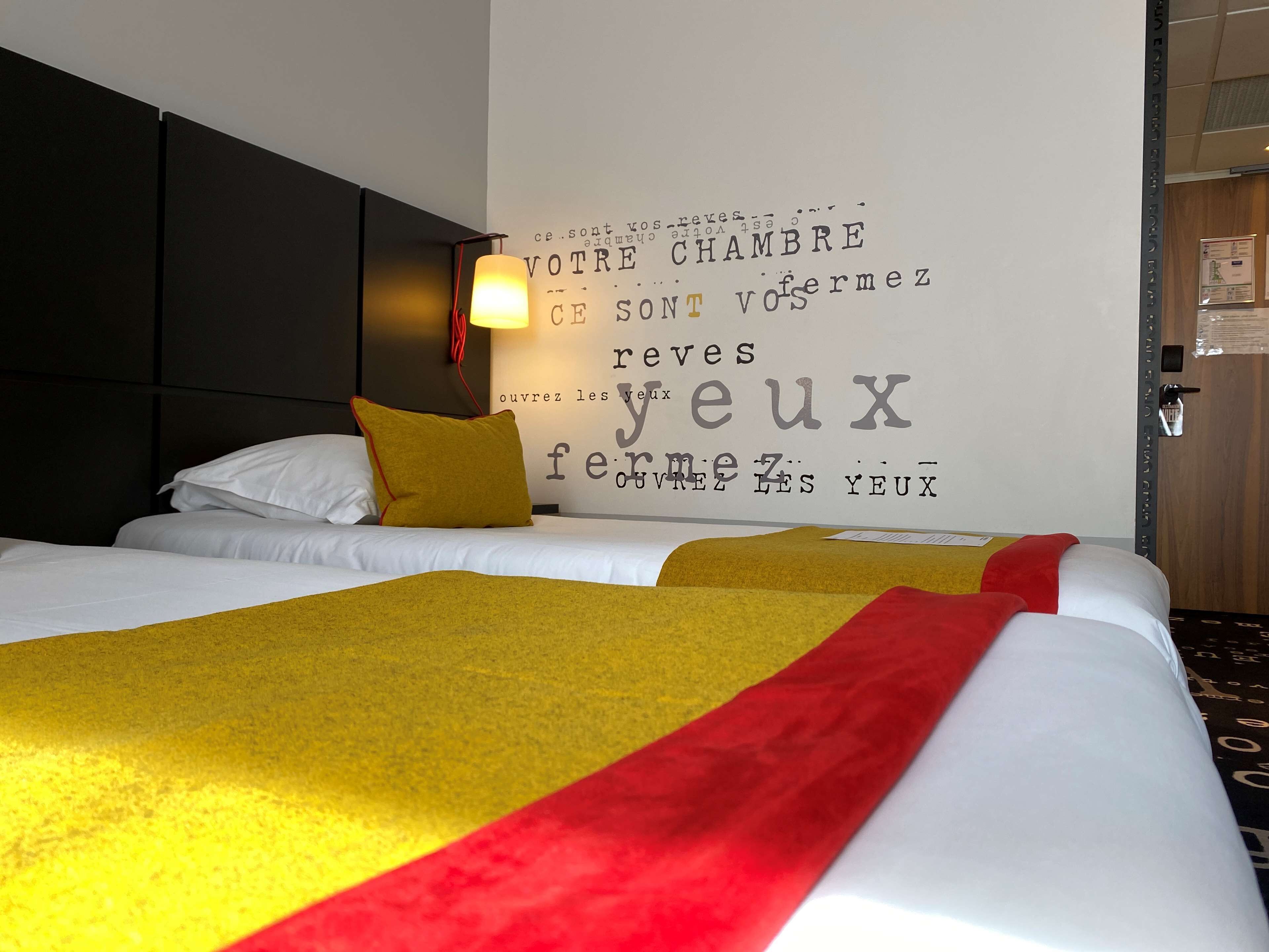 A hotel room with a bed, a wall with text, and a door.