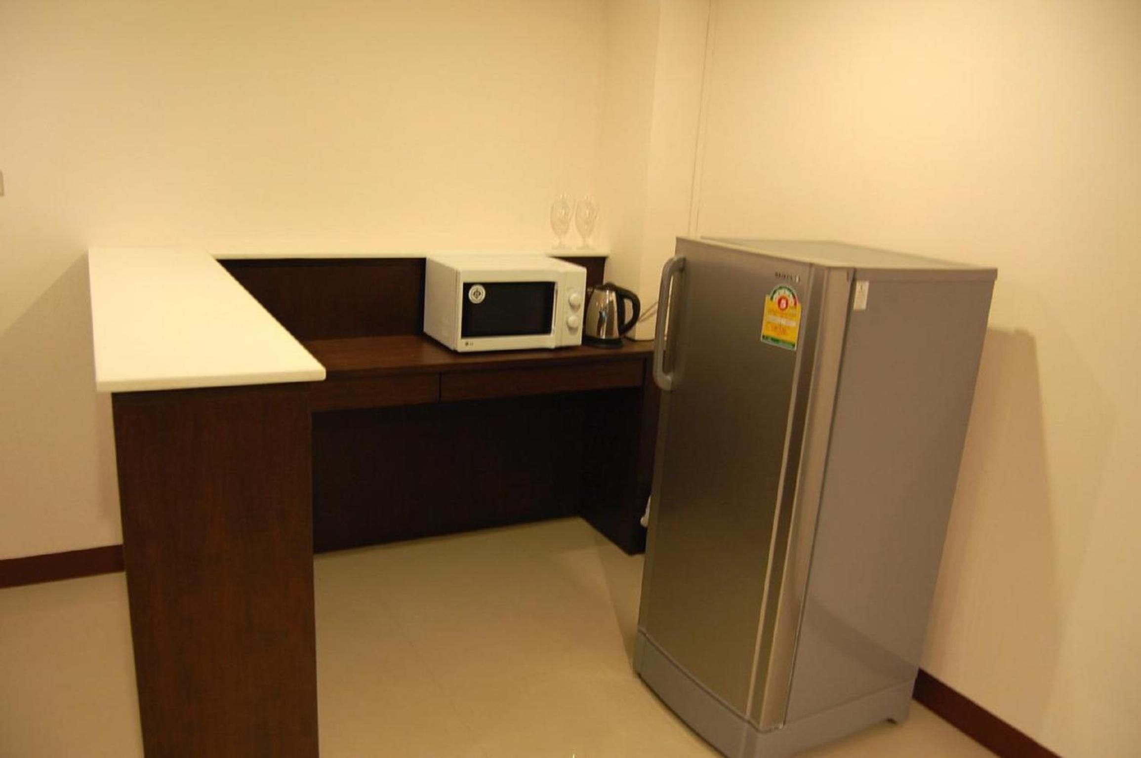 A kitchenette with a microwave, a kettle, and a refrigerator.
