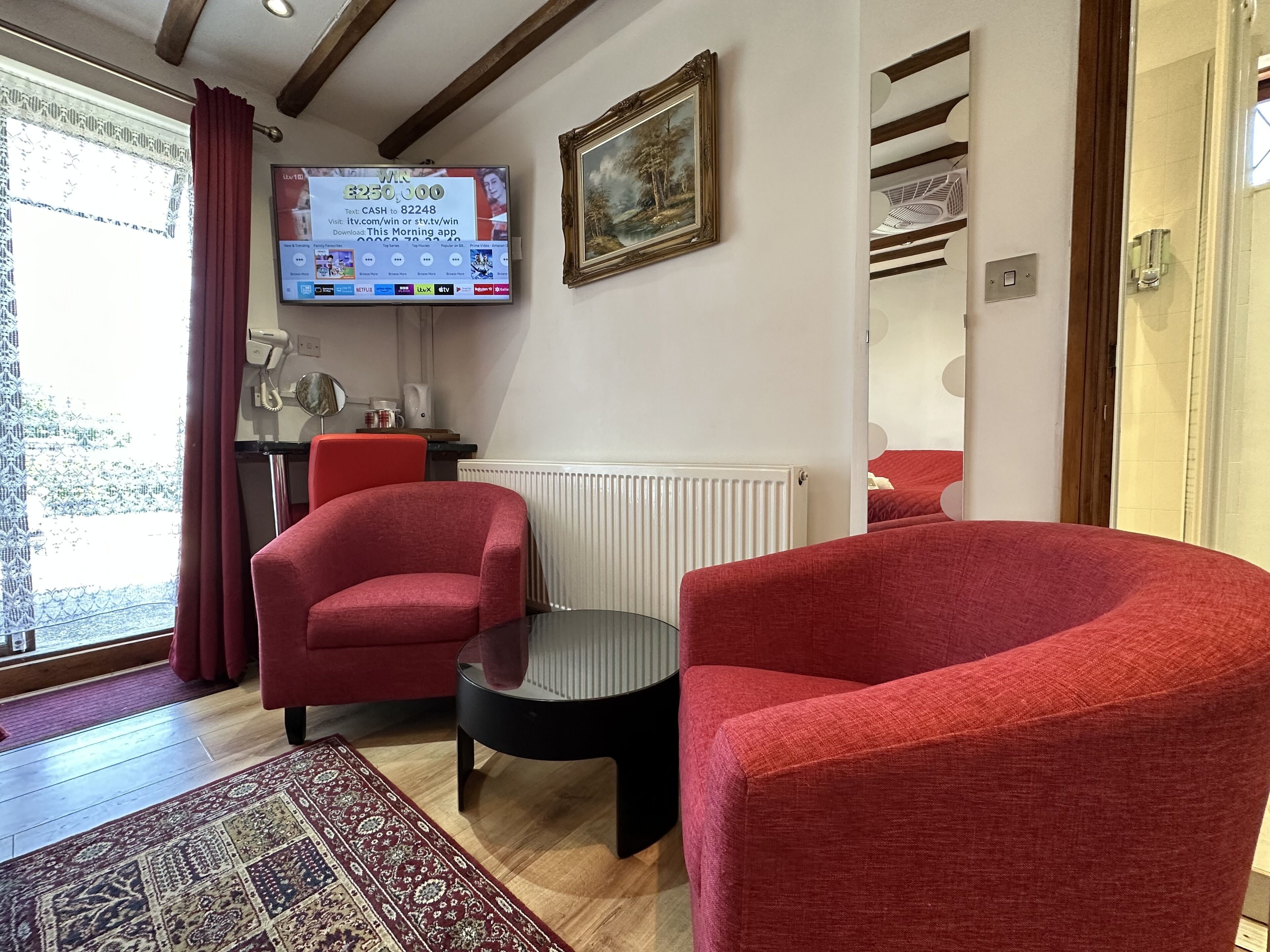 Un soggiorno con poltrone rosse, un tavolino, un termosifone e una TV che mostra una notifica di premio.