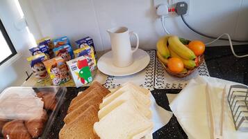 A kitchen counter with breakfast items including bread, eggs, cereal, and fruit.
