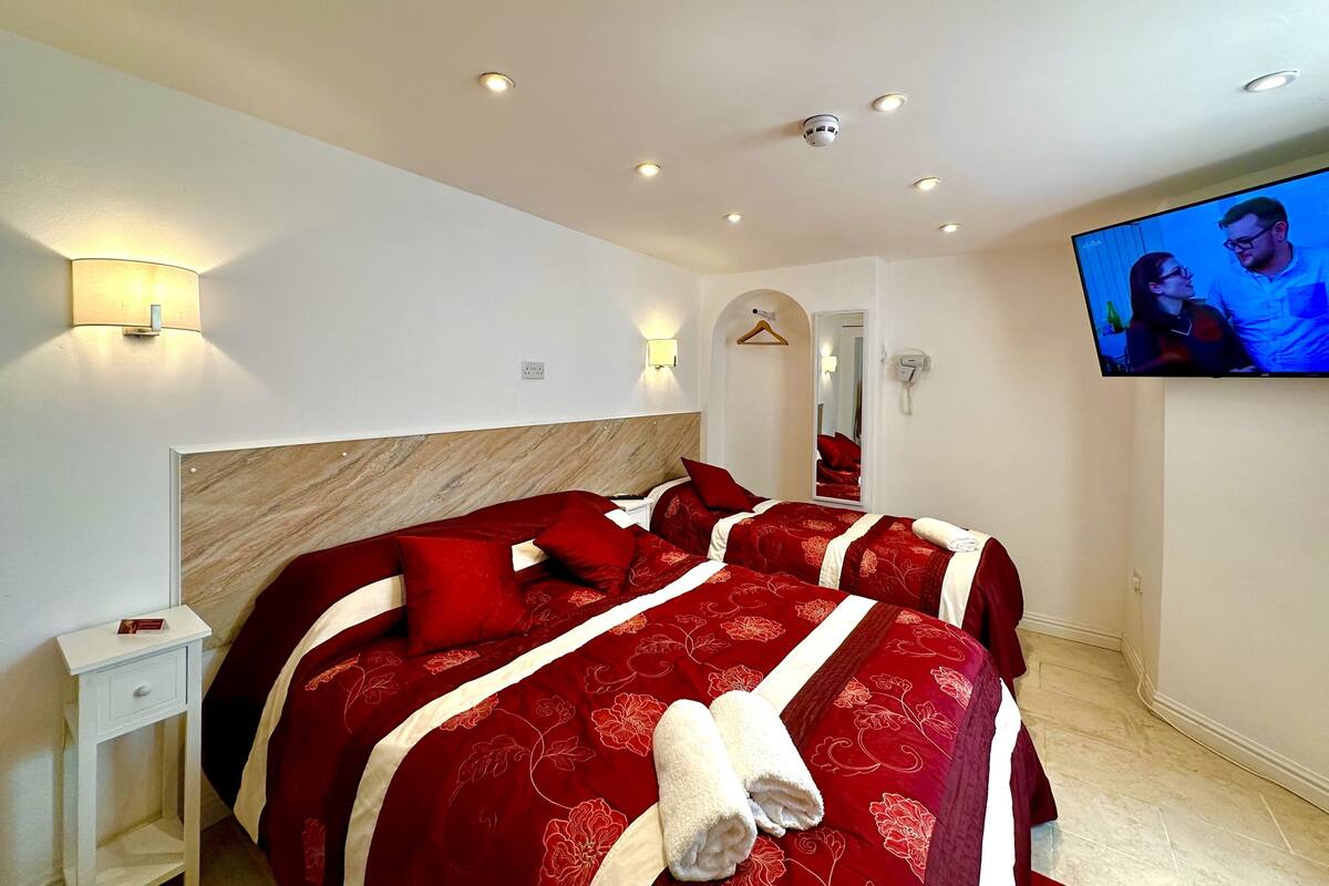 Ein Hotelzimmer mit einem großen Bett, einem an der Wand befestigten Fernseher und einem Spiegel.