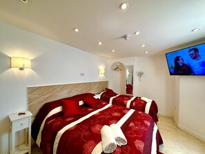 Ein Hotelzimmer mit einem großen Bett, einem an der Wand befestigten Fernseher und einem Spiegel.