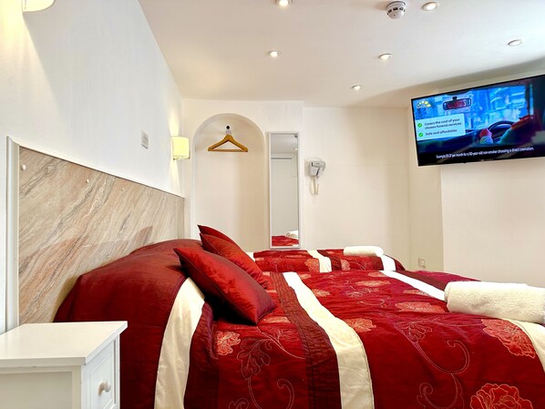 Habitación de hotel con una cama grande, televisión montada en la pared y un teléfono.
