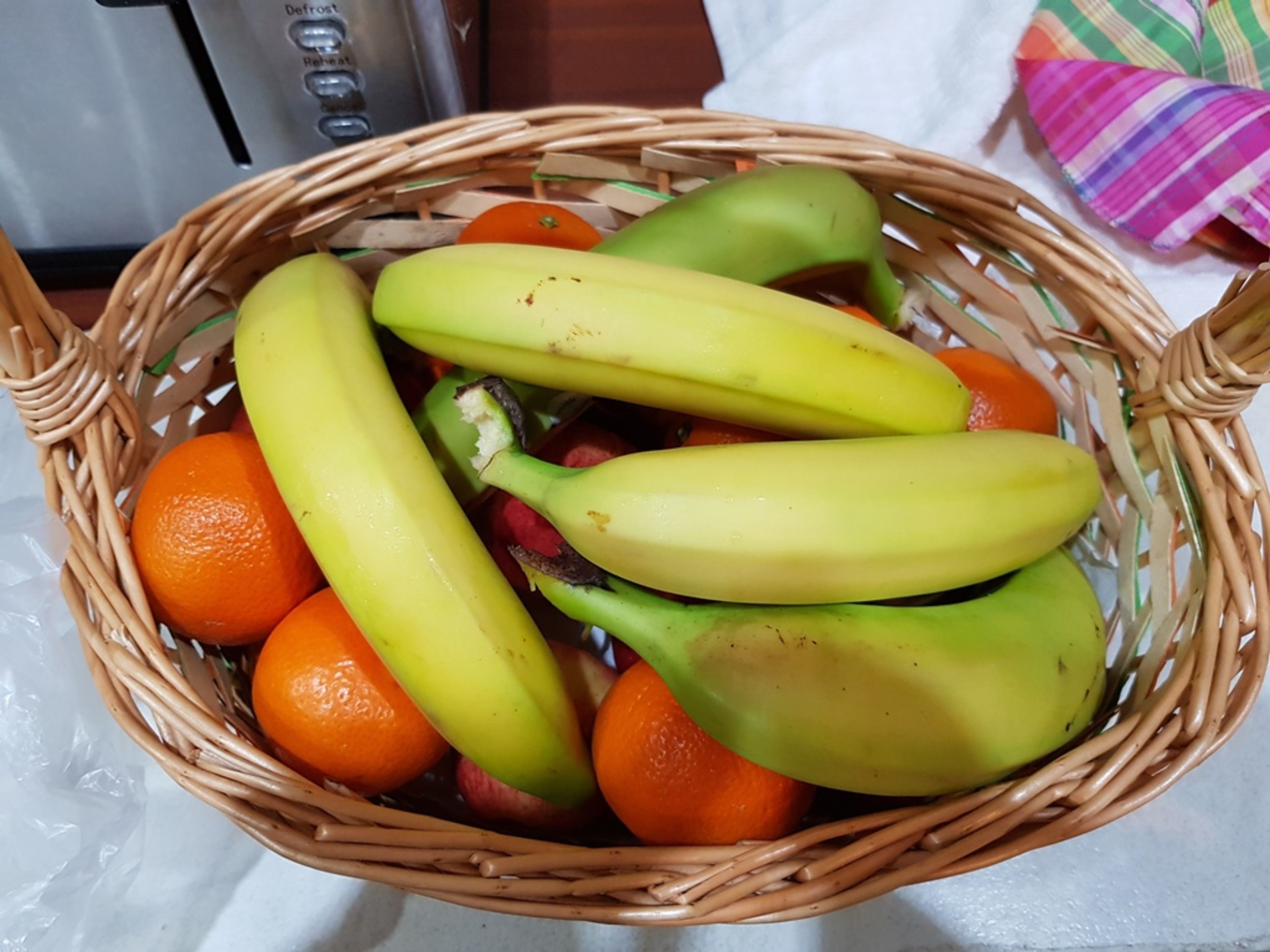 Una cesta de mimbre con plátanos y naranjas.