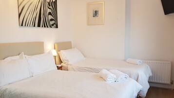 A hotel room with two beds, white linens, a zebra print artwork, a framed picture, and a white radiator.
