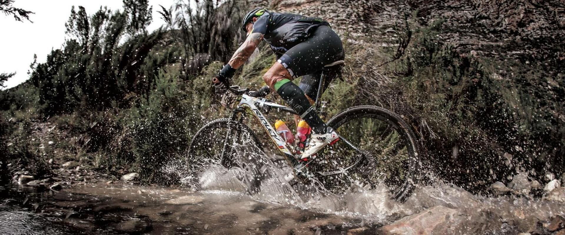 A mountain biker navigating a rocky stream.
