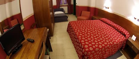 A compact hotel room with a single bed, a desk with a TV, a chair, and a wardrobe.