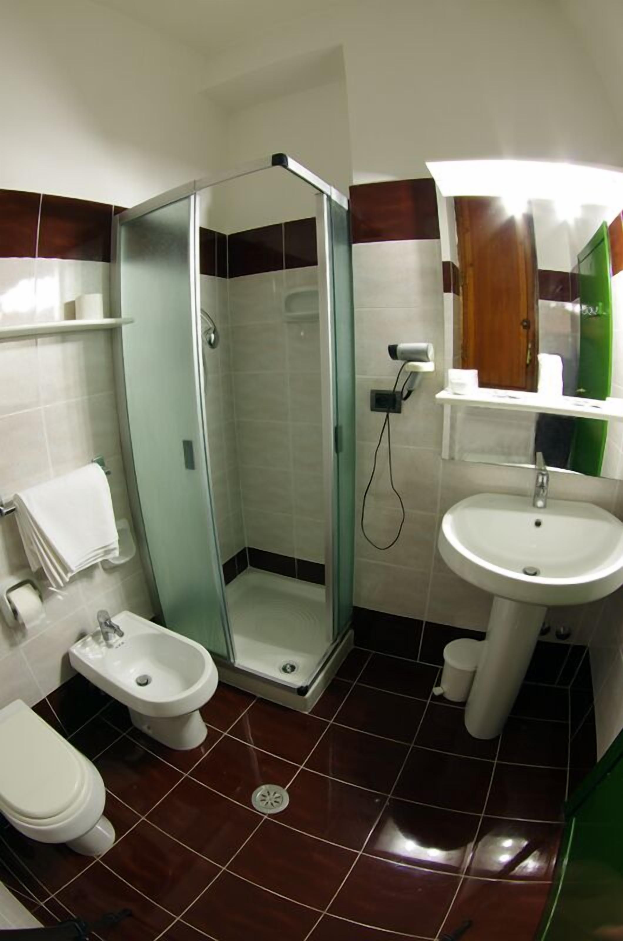 A bathroom with a glass-enclosed shower, a bidet, a sink, and a toilet.