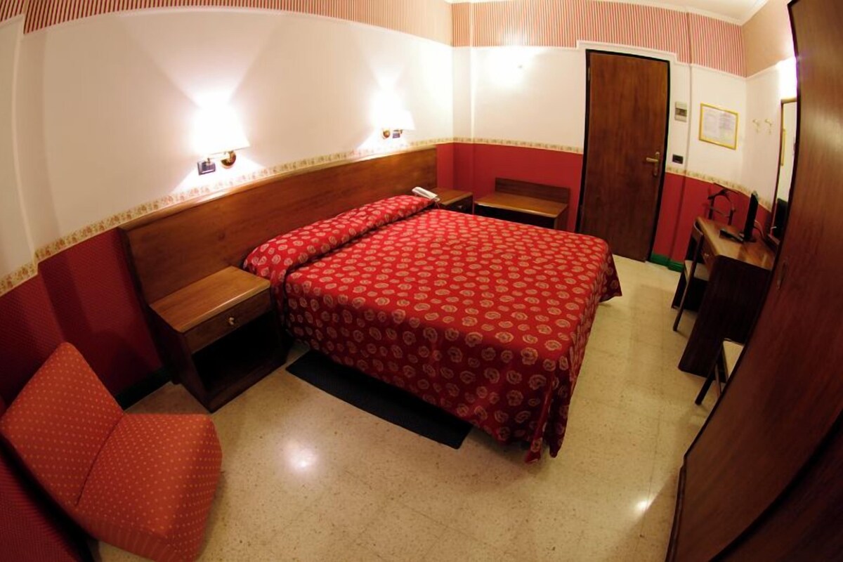 Ein Hotelzimmer mit Bett, Stuhl, Schreibtisch und Kleiderschrank.