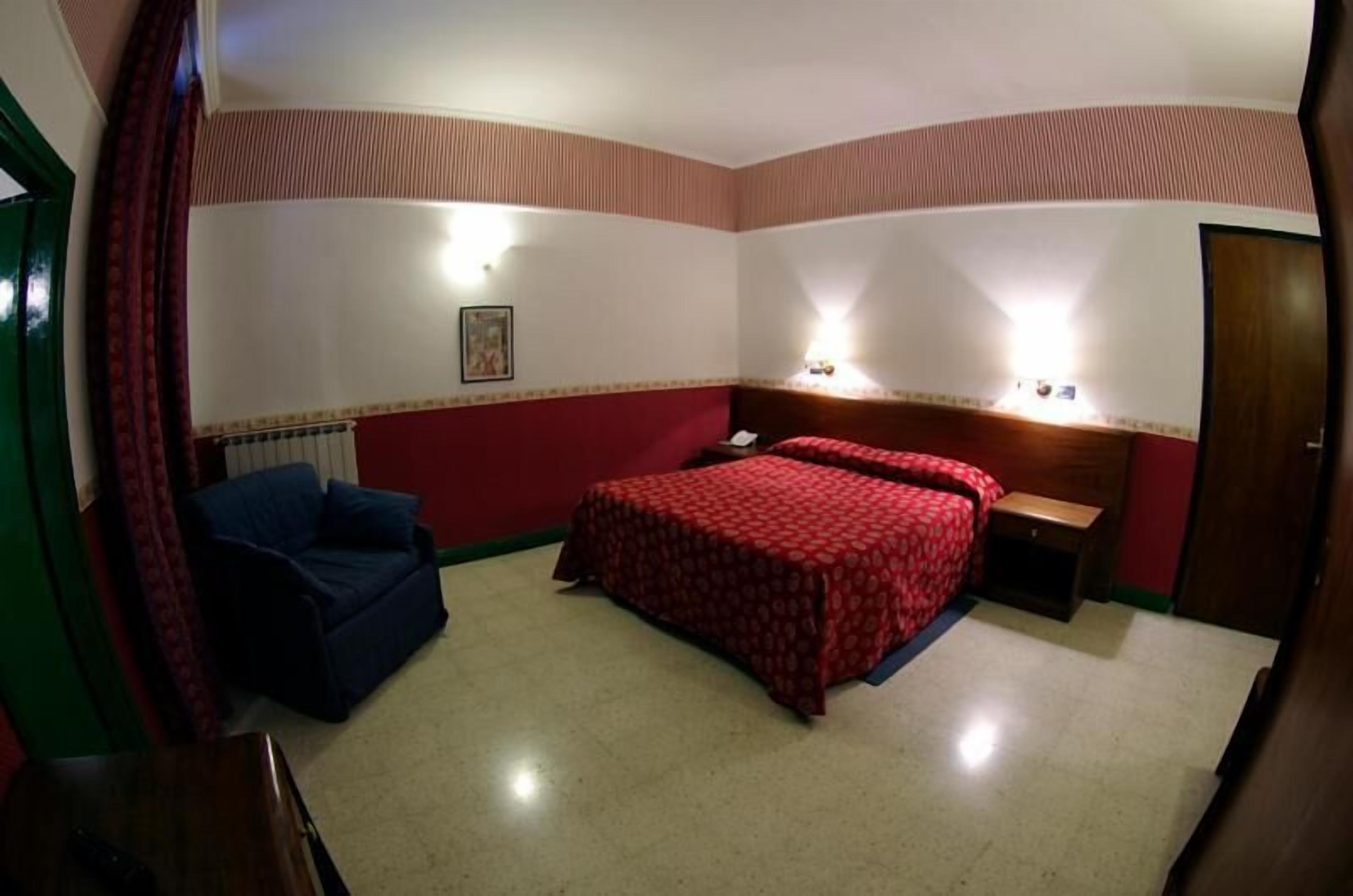 A hotel room with a bed, a desk, and a chair.