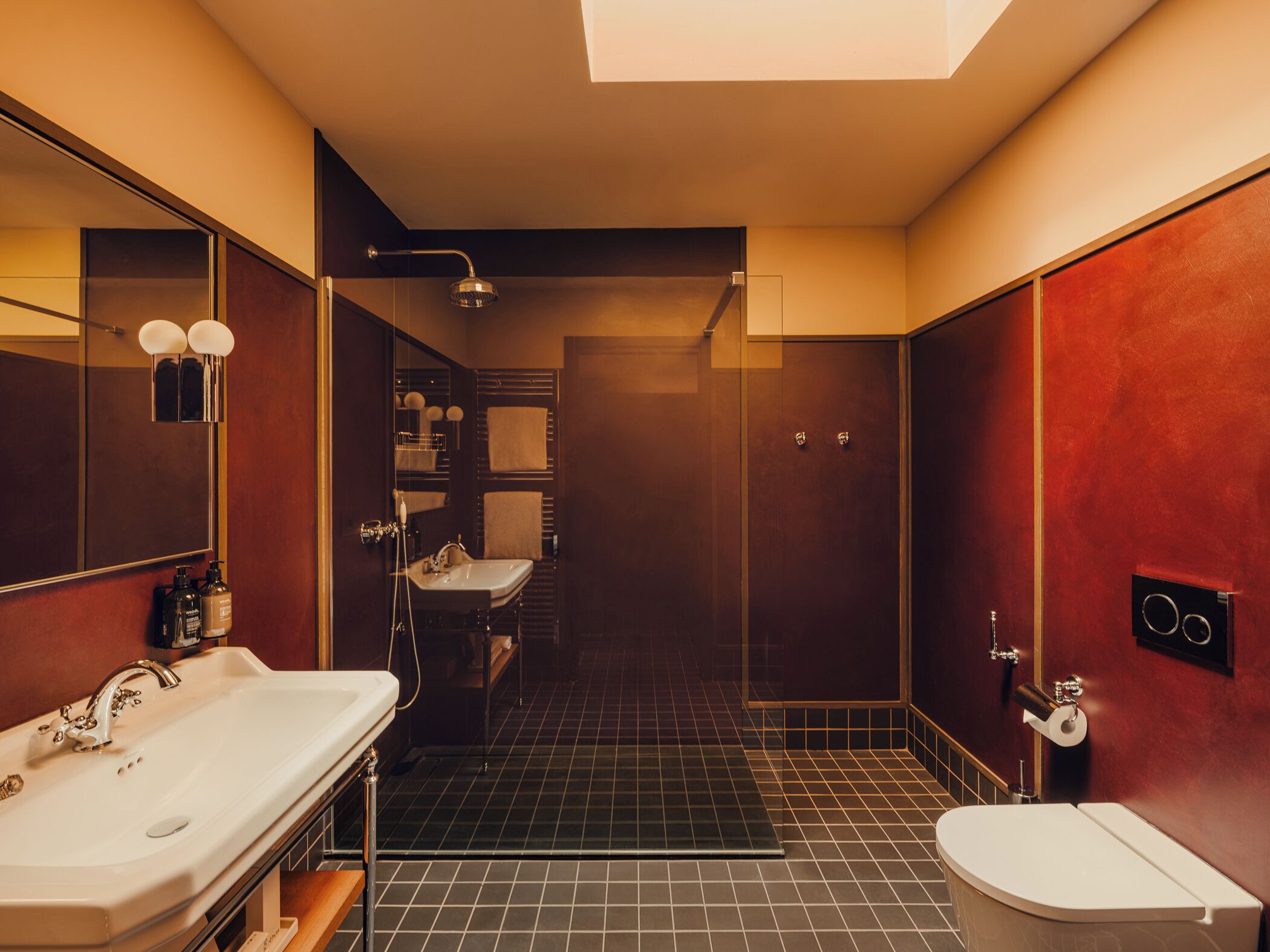 Un baño moderno con un espejo grande, dos lavamanos, ducha y retrete.
