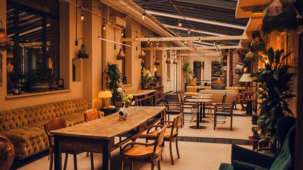 A spacious interior with a long dining table, multiple chairs, a sofa, and a variety of plants. - Aethos Hotel Milan (Milan)