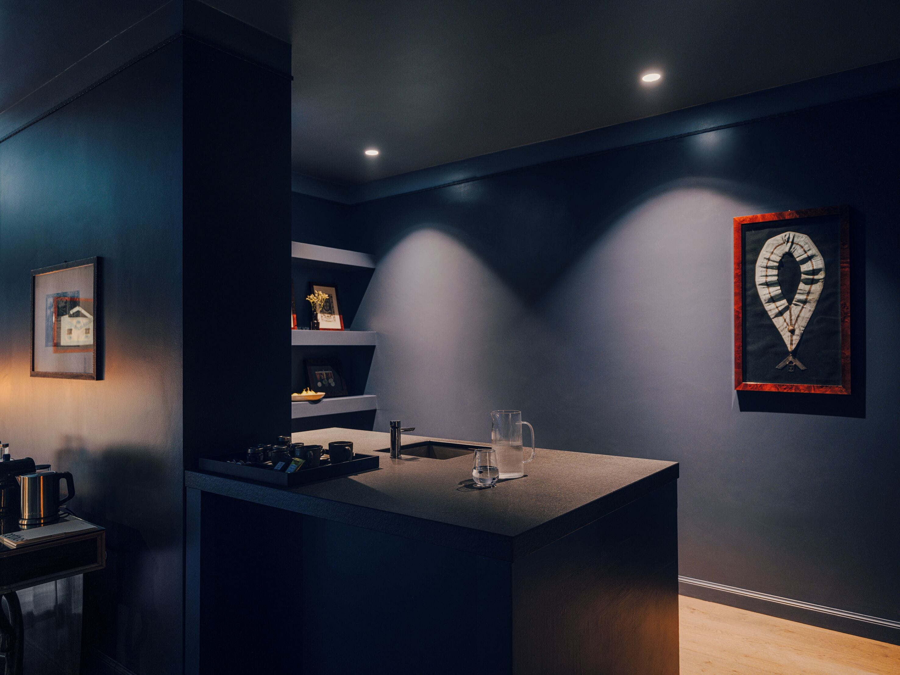 Eine moderne Küche mit Bar, eingebauten Regalen und einem gerahmten Kunstwerk an der Wand.