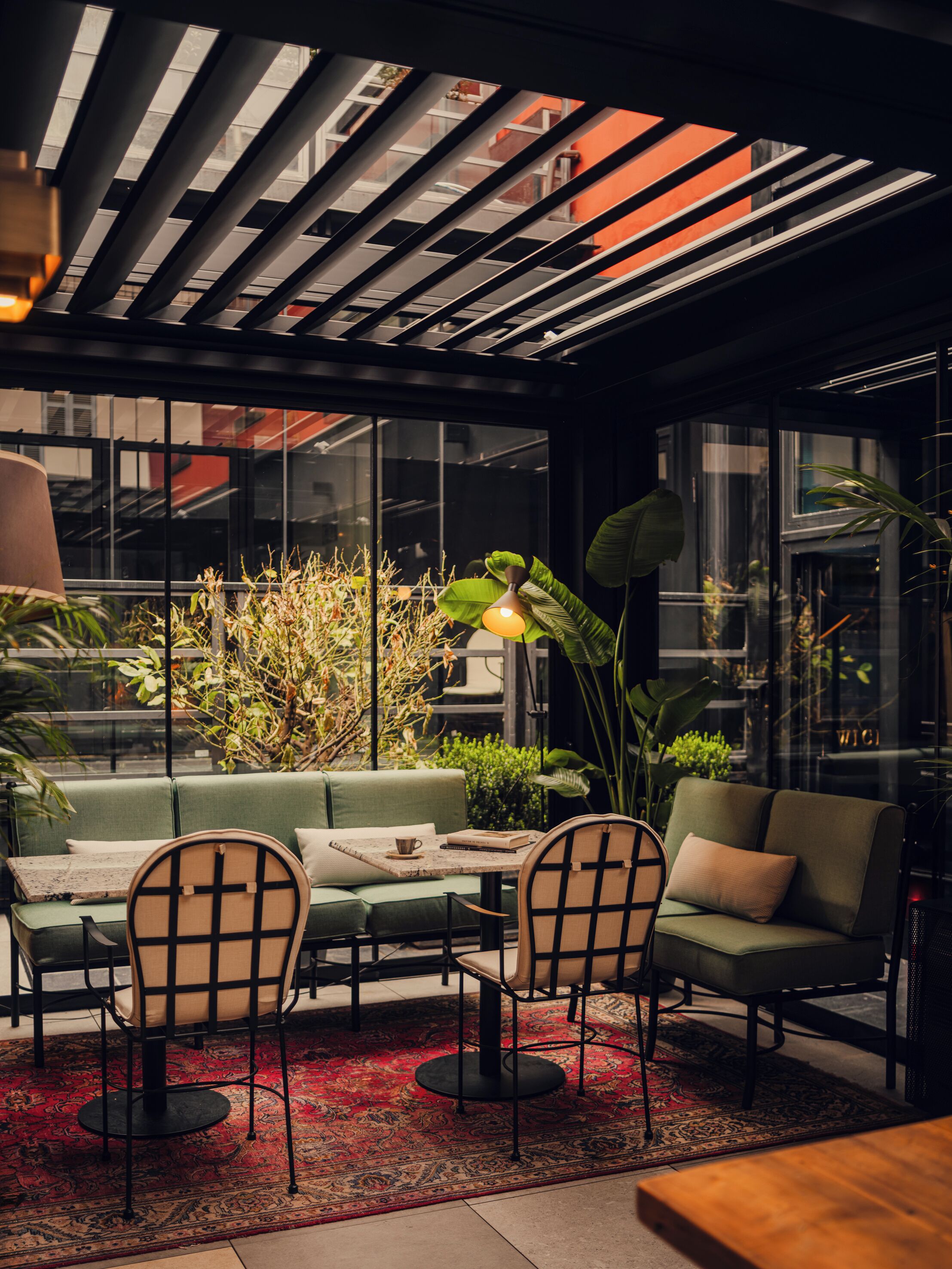 Un intérieur moderne avec un canapé vert, deux fauteuils, une petite table et une grande plante.