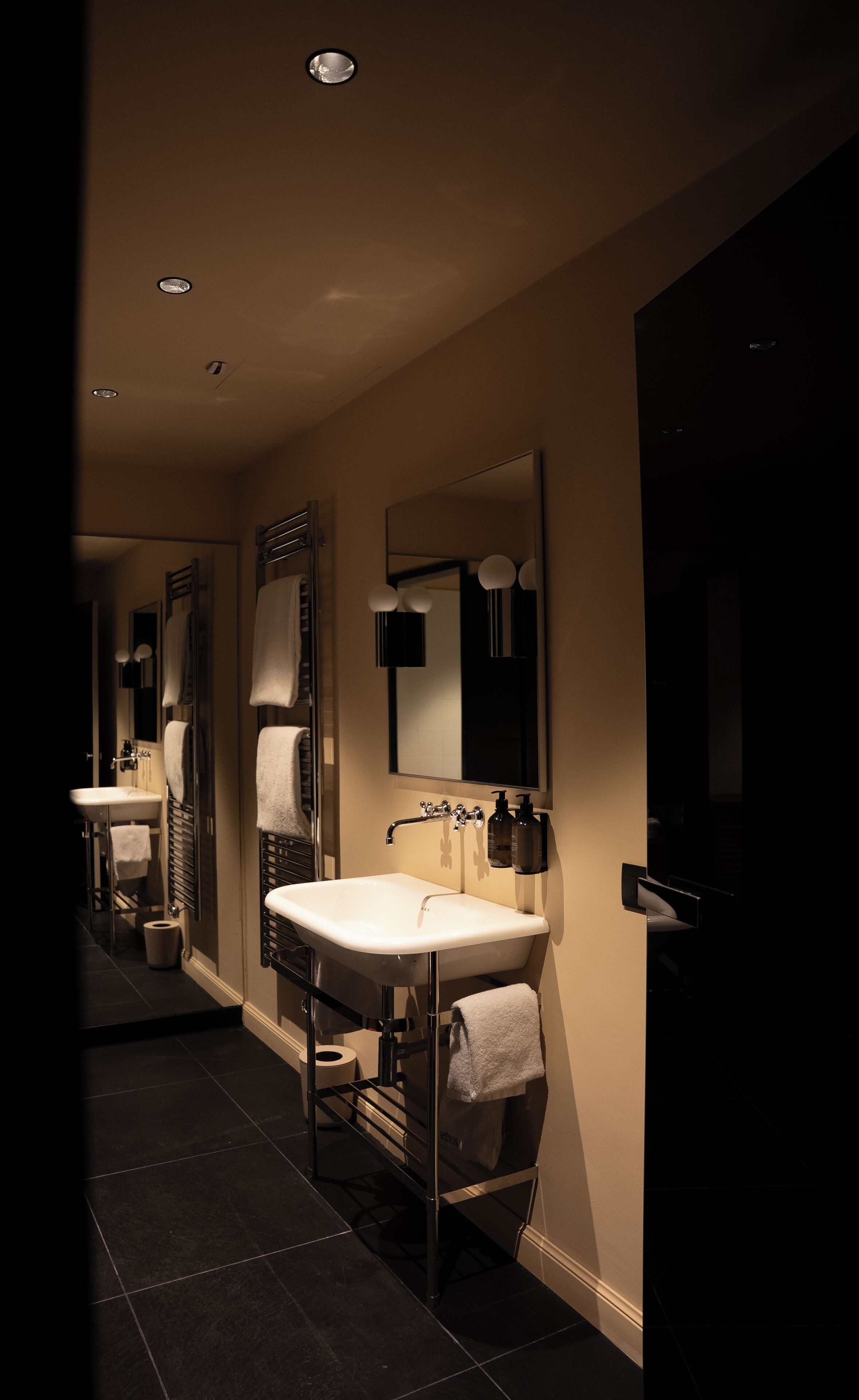 A modern bathroom with two sinks, a large mirror, and a walk-in shower.