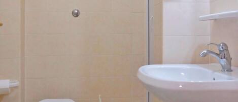 A bathroom with a toilet, bidet, sink, and shower.