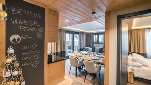 A modern hotel room with a wooden ceiling, a dining area with a table set for two, and a cozy sitting area with a sofa. - Good Value Apartments by MX Zermatt (Zermatt)