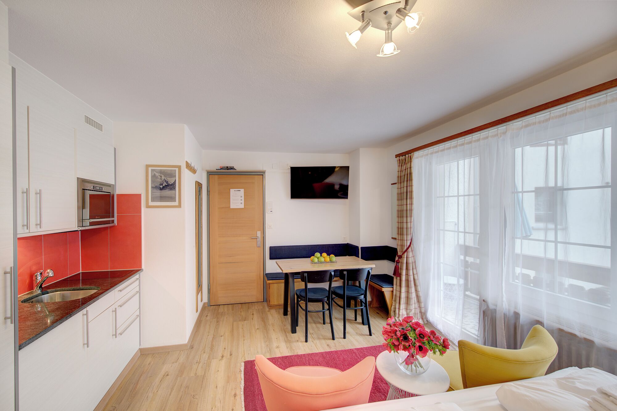 Camera d'albergo compatta con angolo cottura, zona pranzo e letto con vista.