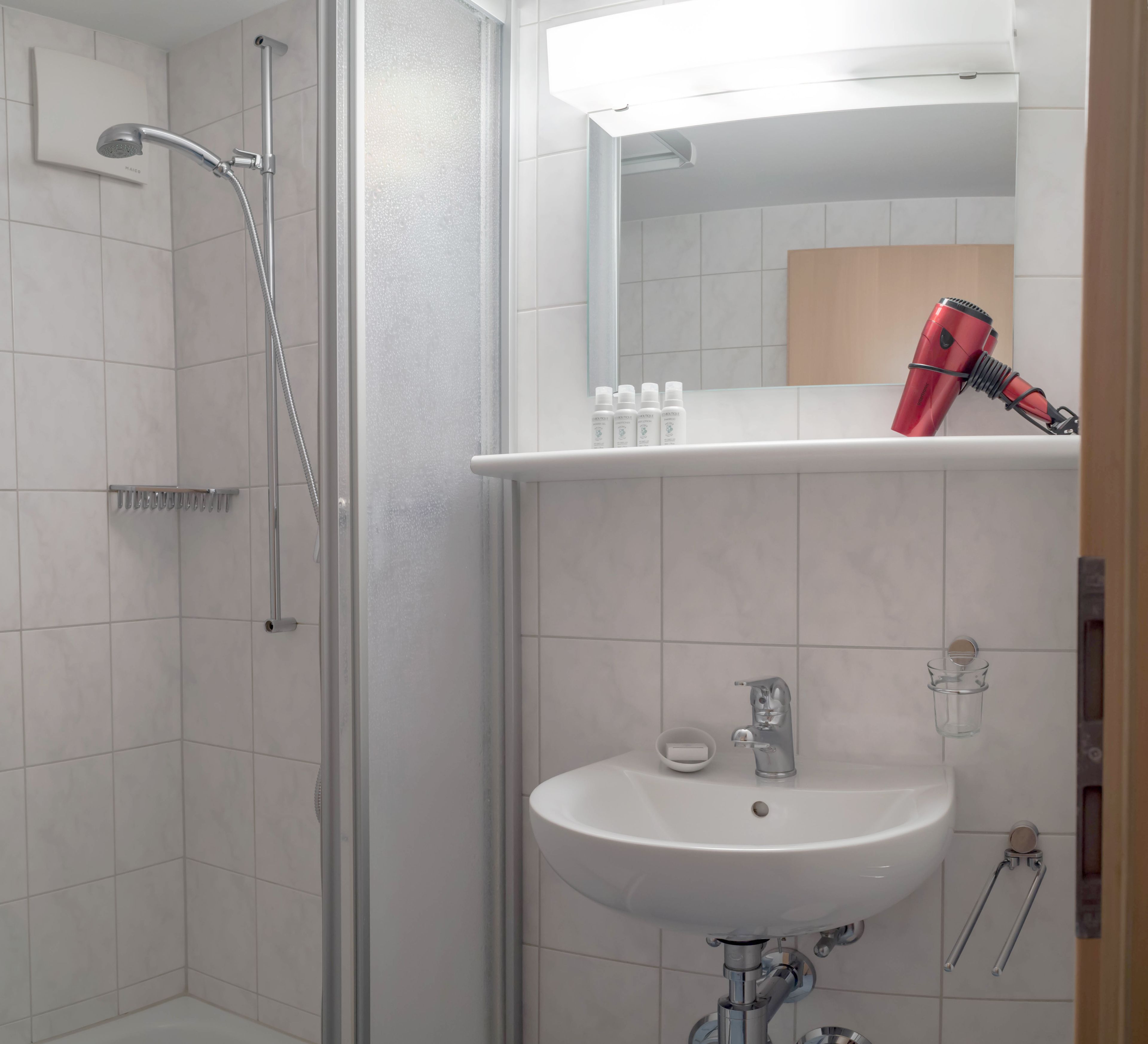 Ein modernes Badezimmer mit Dusche, Waschbecken und einem Spiegel darüber.