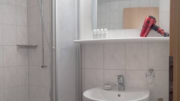 Ein modernes Badezimmer mit Dusche, Waschbecken und einem Spiegel darüber.
