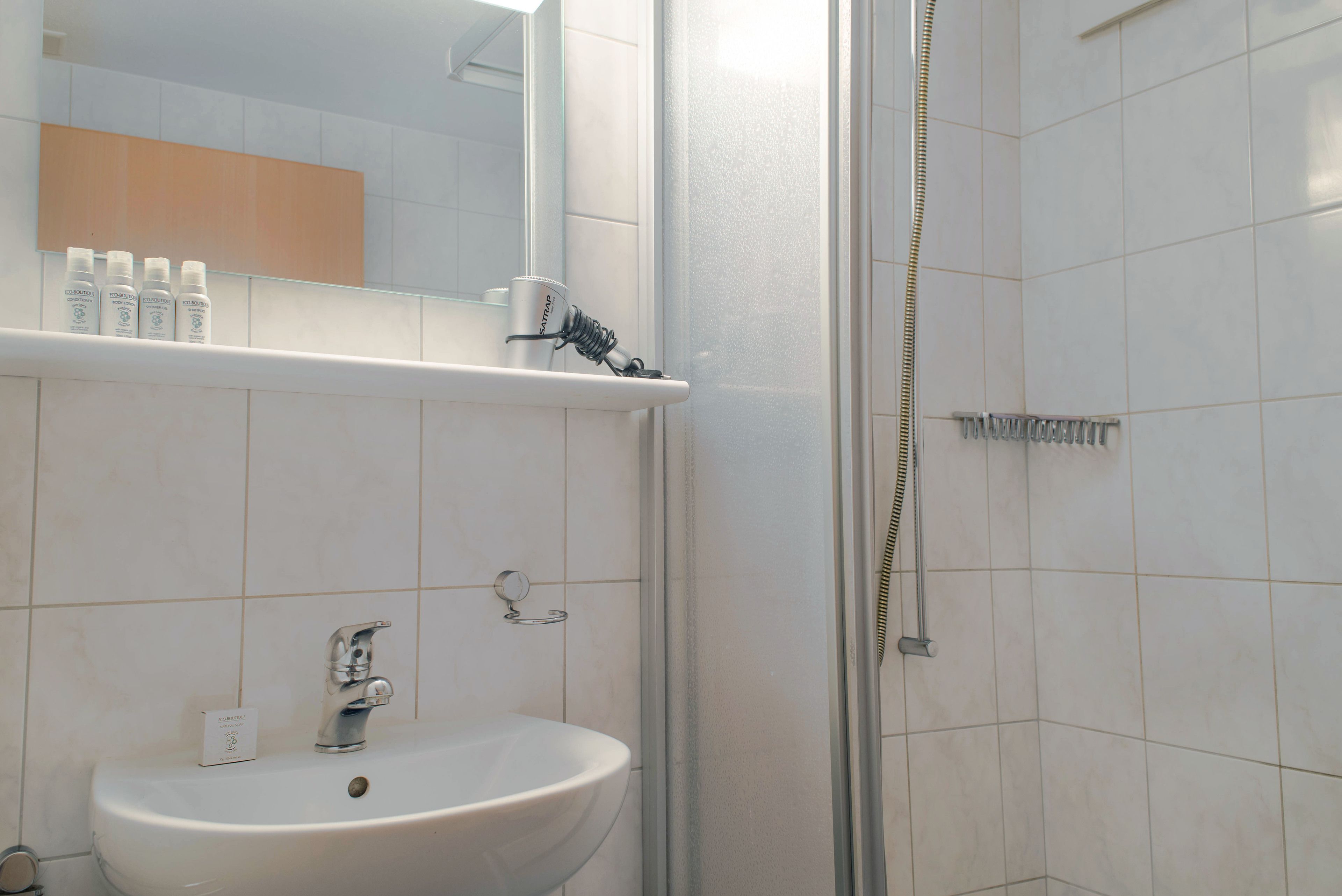 Un baño con lavabo, espejo y ducha.