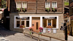 A traditional chalet-style building with a wooden facade, two visible windows with flower boxes, and a sign indicating it is a luxury chalet rental. - Good Value Apartments by MX Zermatt (Zermatt)