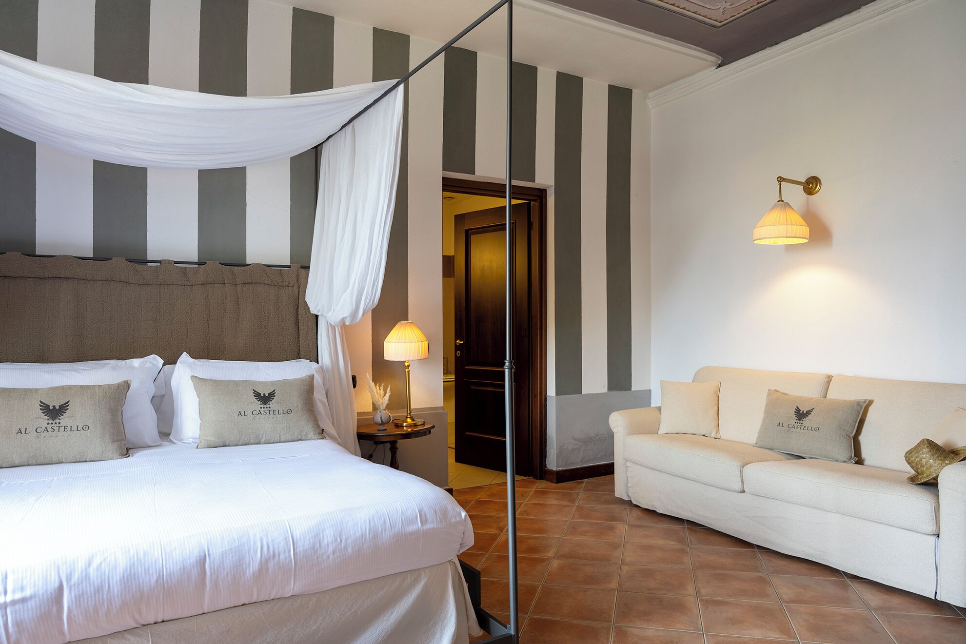 Una camera d'albergo con un letto, un divano, una lampada e una porta.