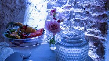 A table with a fruit bowl, a vase with a flower, and a water dispenser.