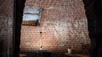 Un four en briques avec une cheminée, un foyer en pierre et une marmite posée sur une étagère.